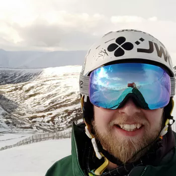 Me grinning at the camera in ski gear with Glenshee ski centre in background