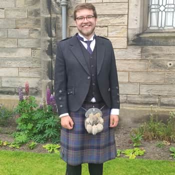 Me posing outside in full highland dress with blue-purple kilt